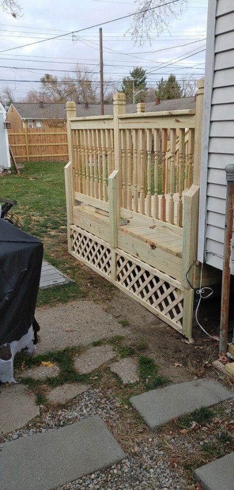A wooden fence is sitting next to a house in a backyard.