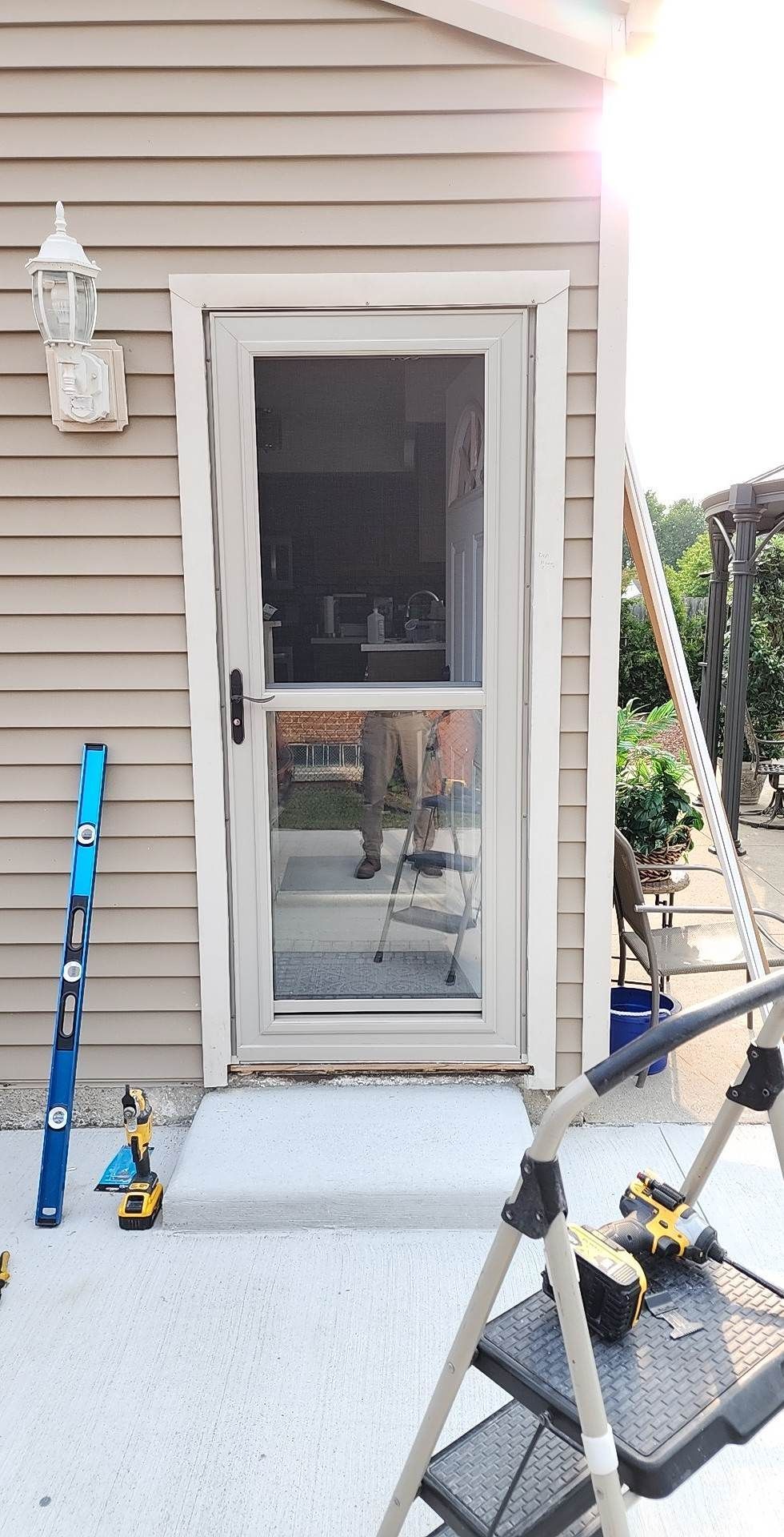 A screen door is being installed on the side of a house.