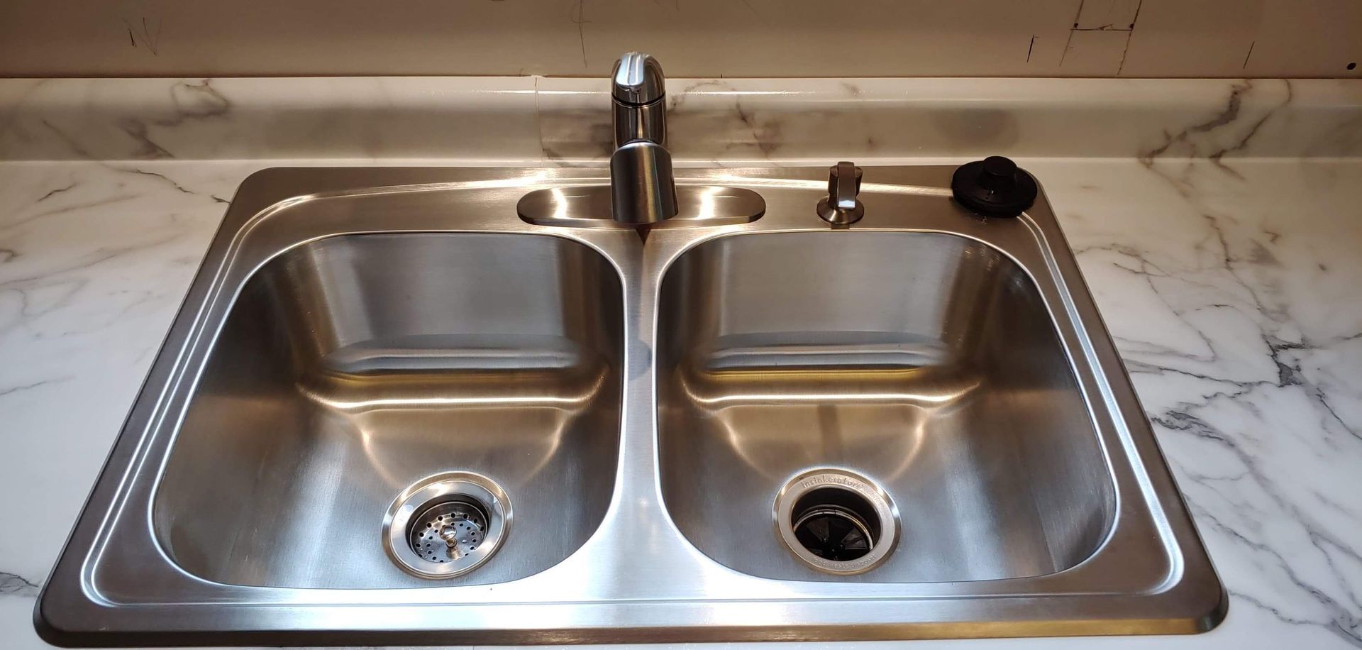 A stainless steel kitchen sink with two sinks and a faucet
