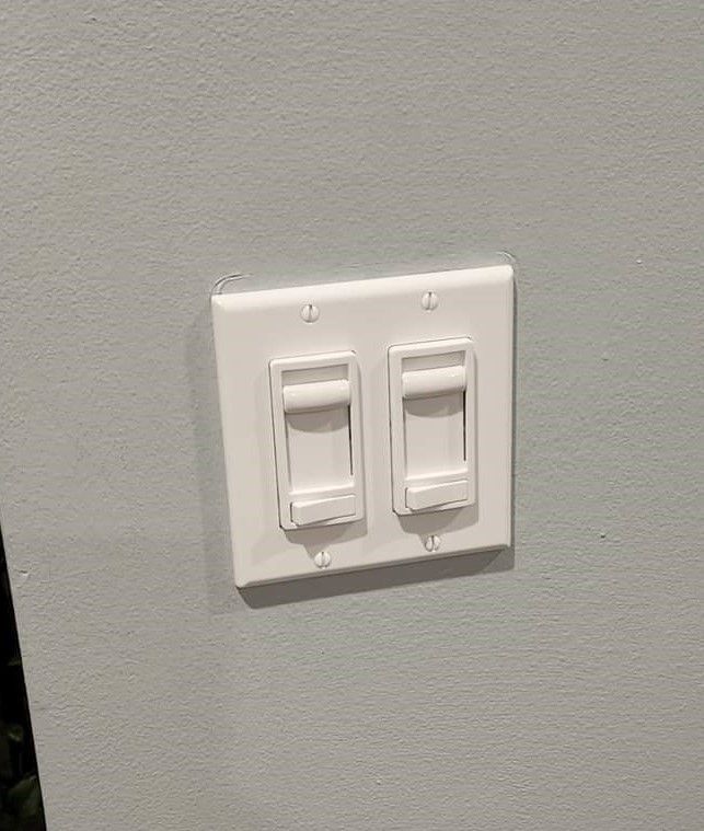 A white light switch is mounted on a gray wall.