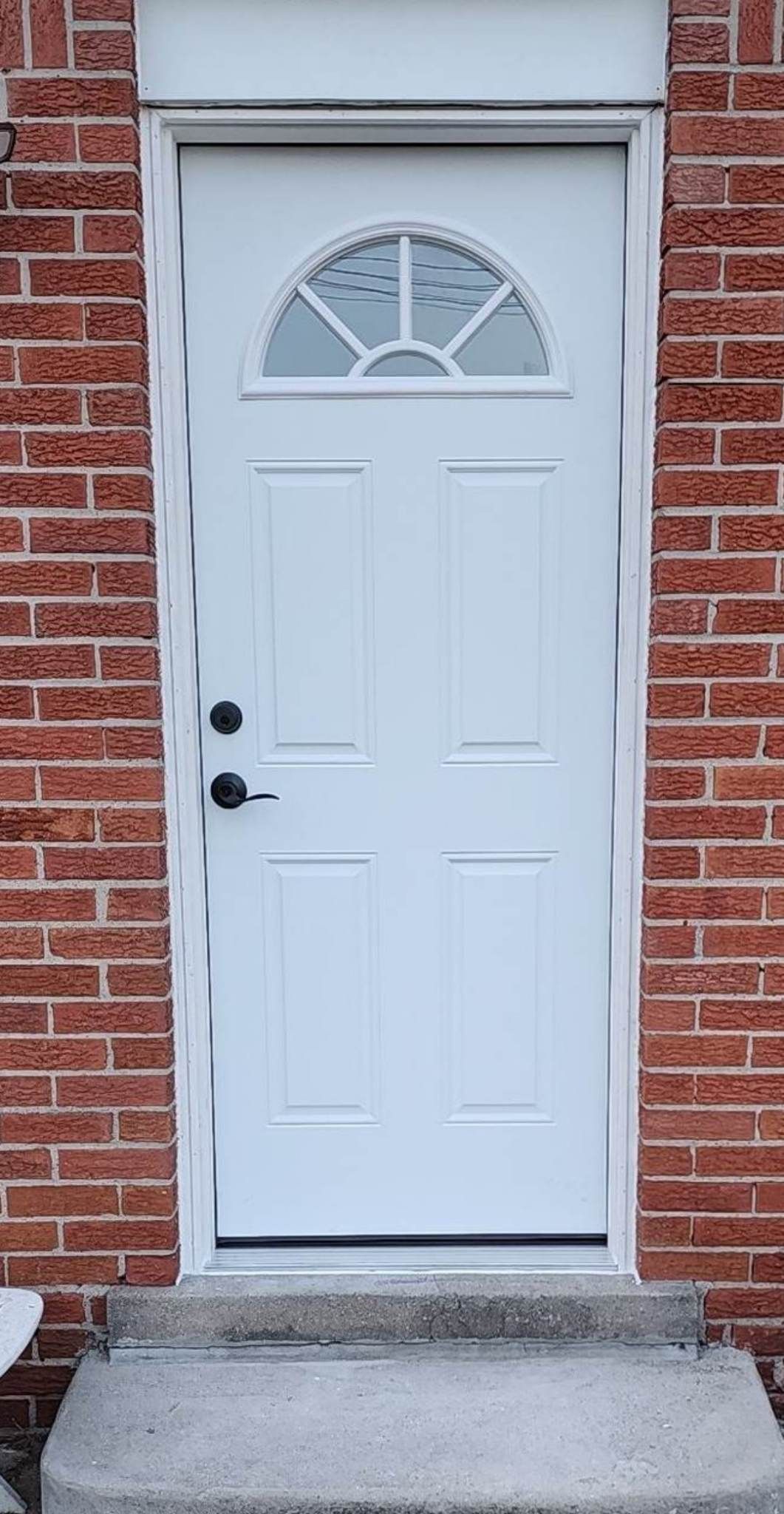 A white door is on a red brick wall