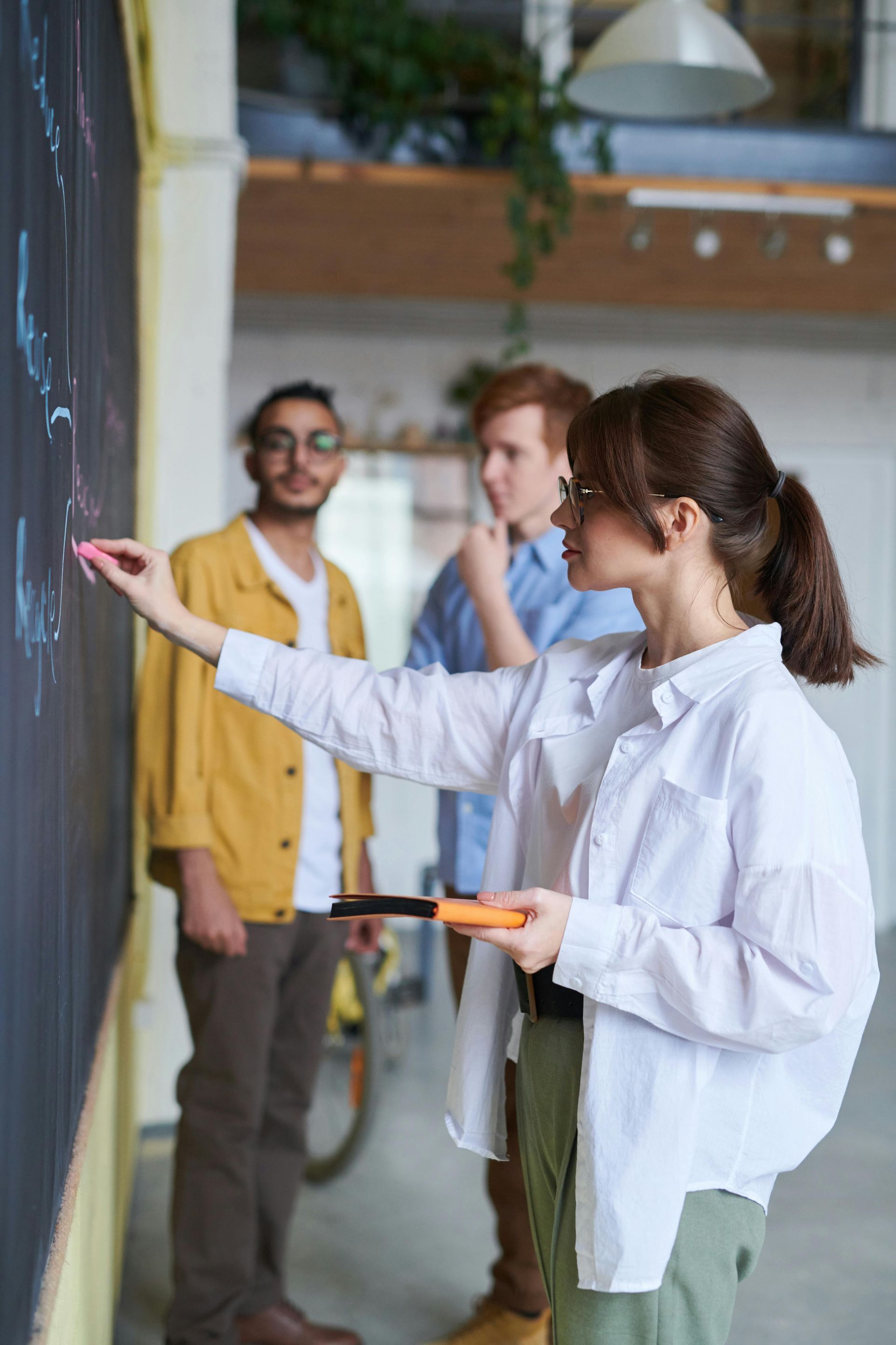 A woman is writing on a blackboard in front of a group of people.