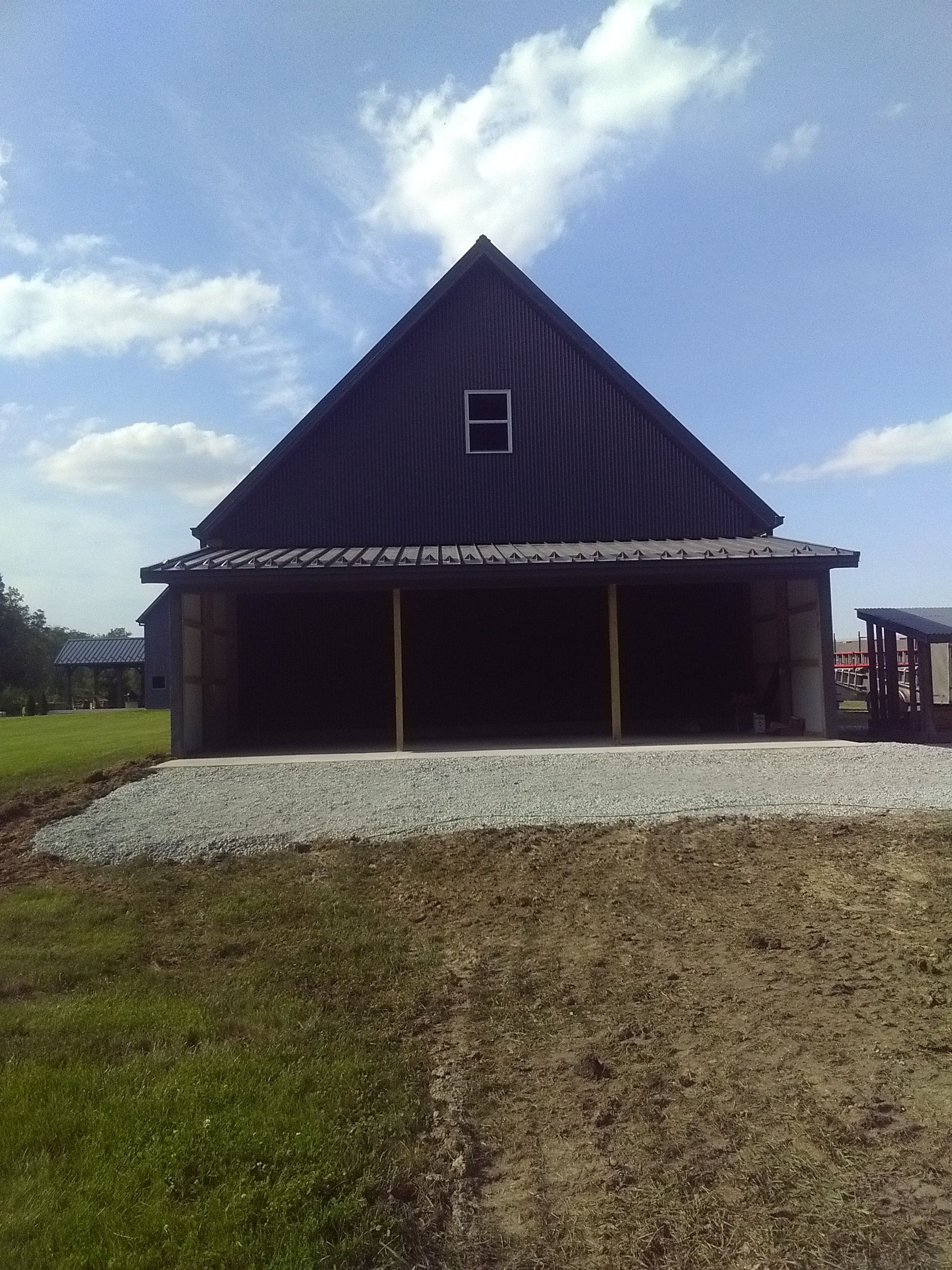 A black barn with a roof that has a window