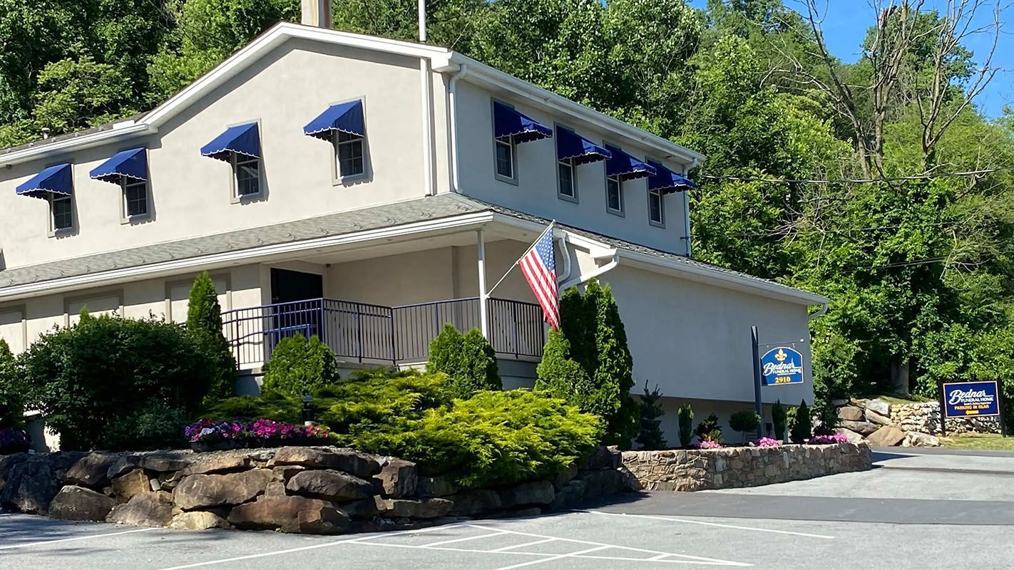 Building with blue awnings, American flag, surrounded by greenery.