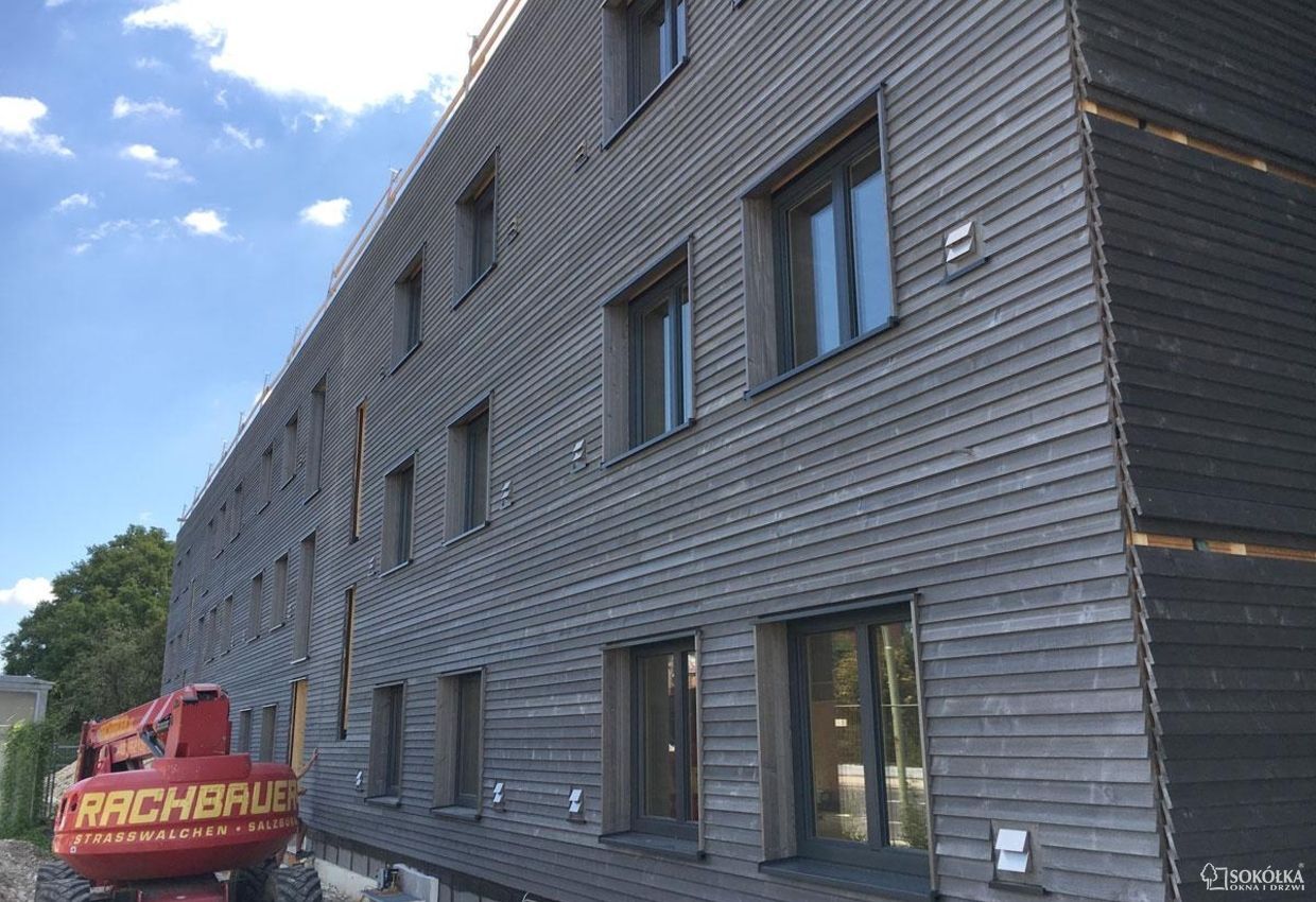 a red tractor is parked in front of a building that says rachbaue