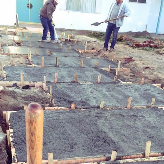 Two men are working on a concrete walkway