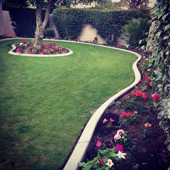 A lush green lawn with flowers and a tree in the middle