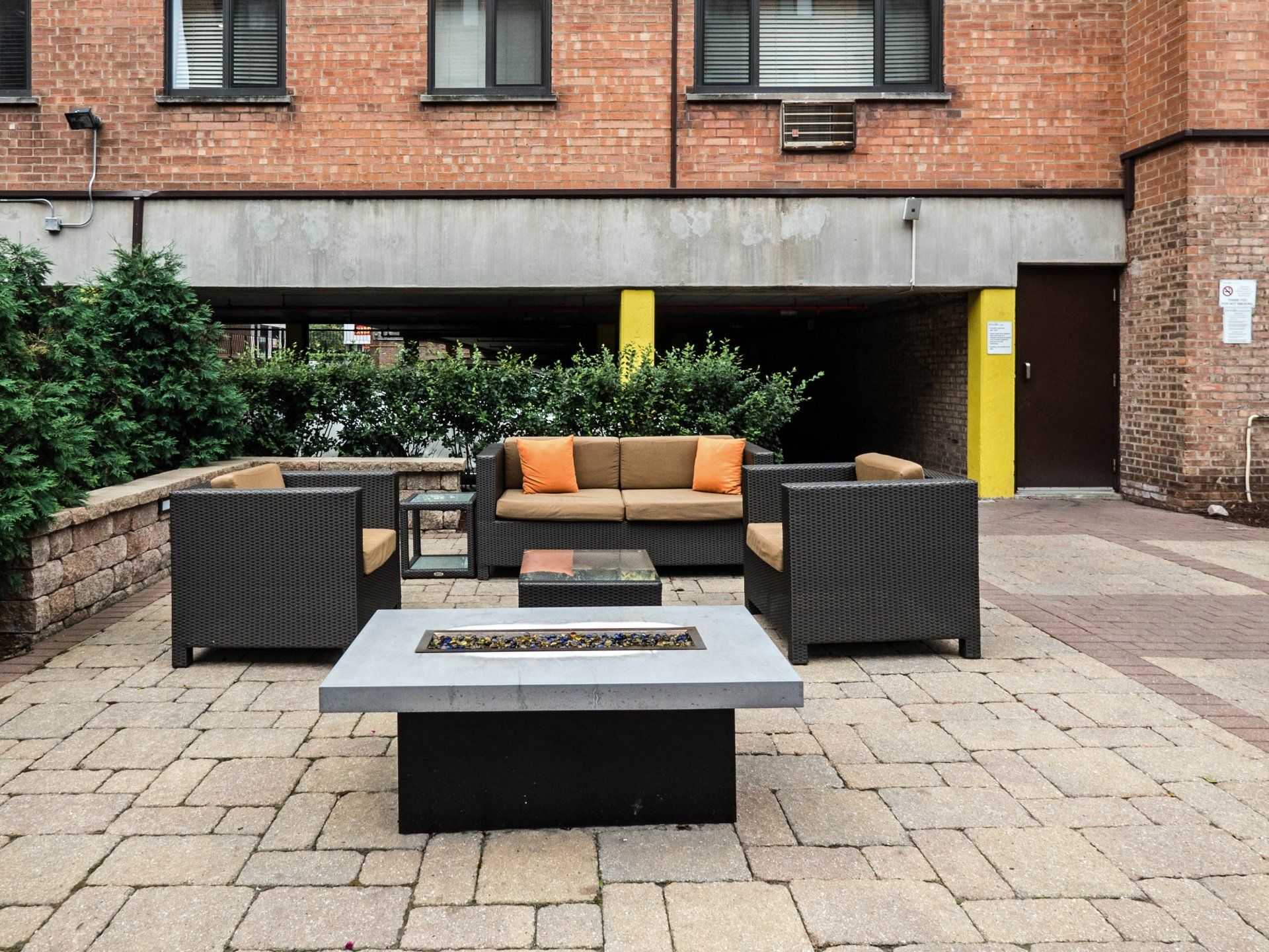 A patio with furniture and a fire pit in front of a brick building at Reside on Morse.