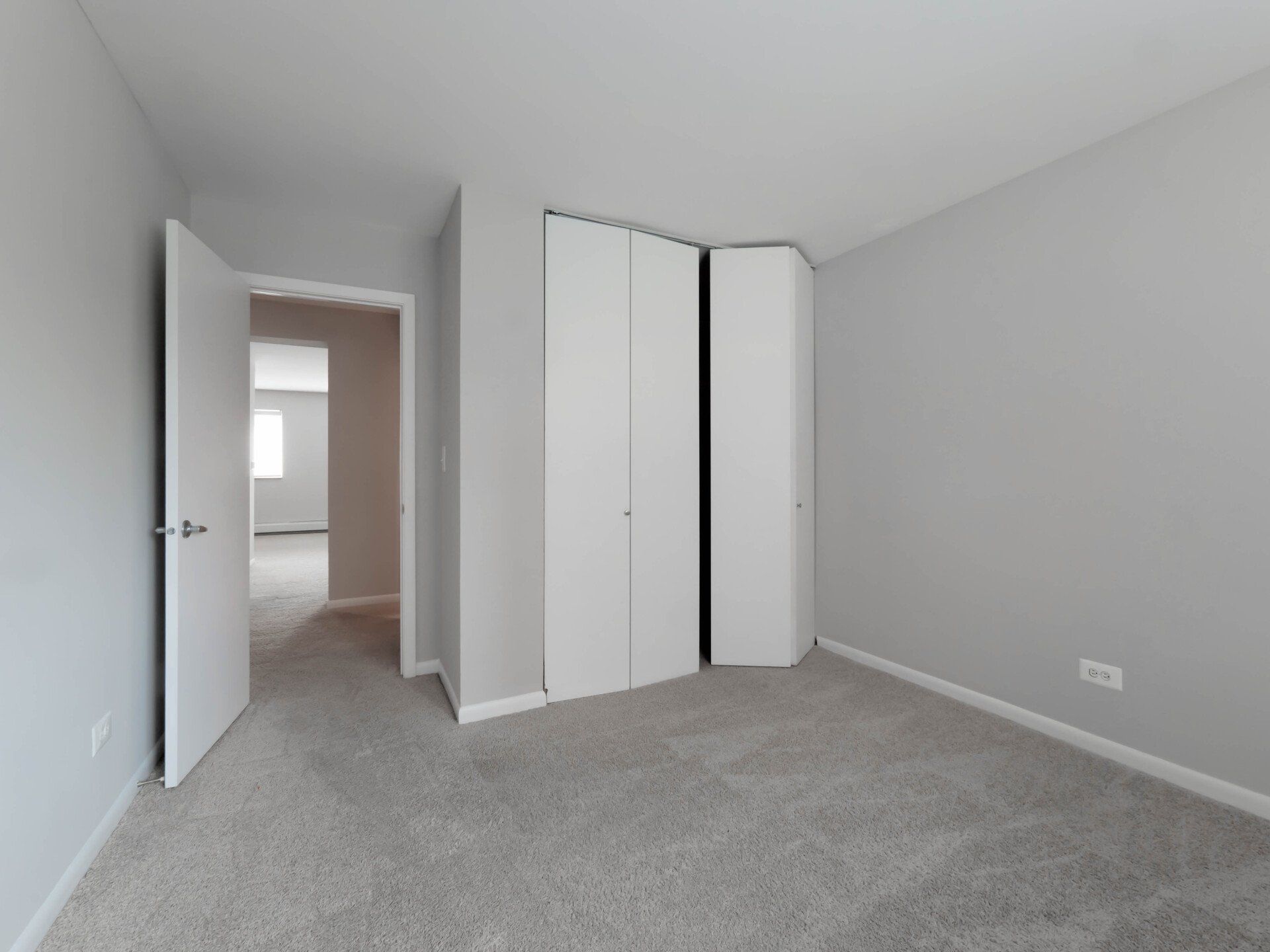 An empty bedroom with a carpeted floor and white walls at Reside on Morse.
