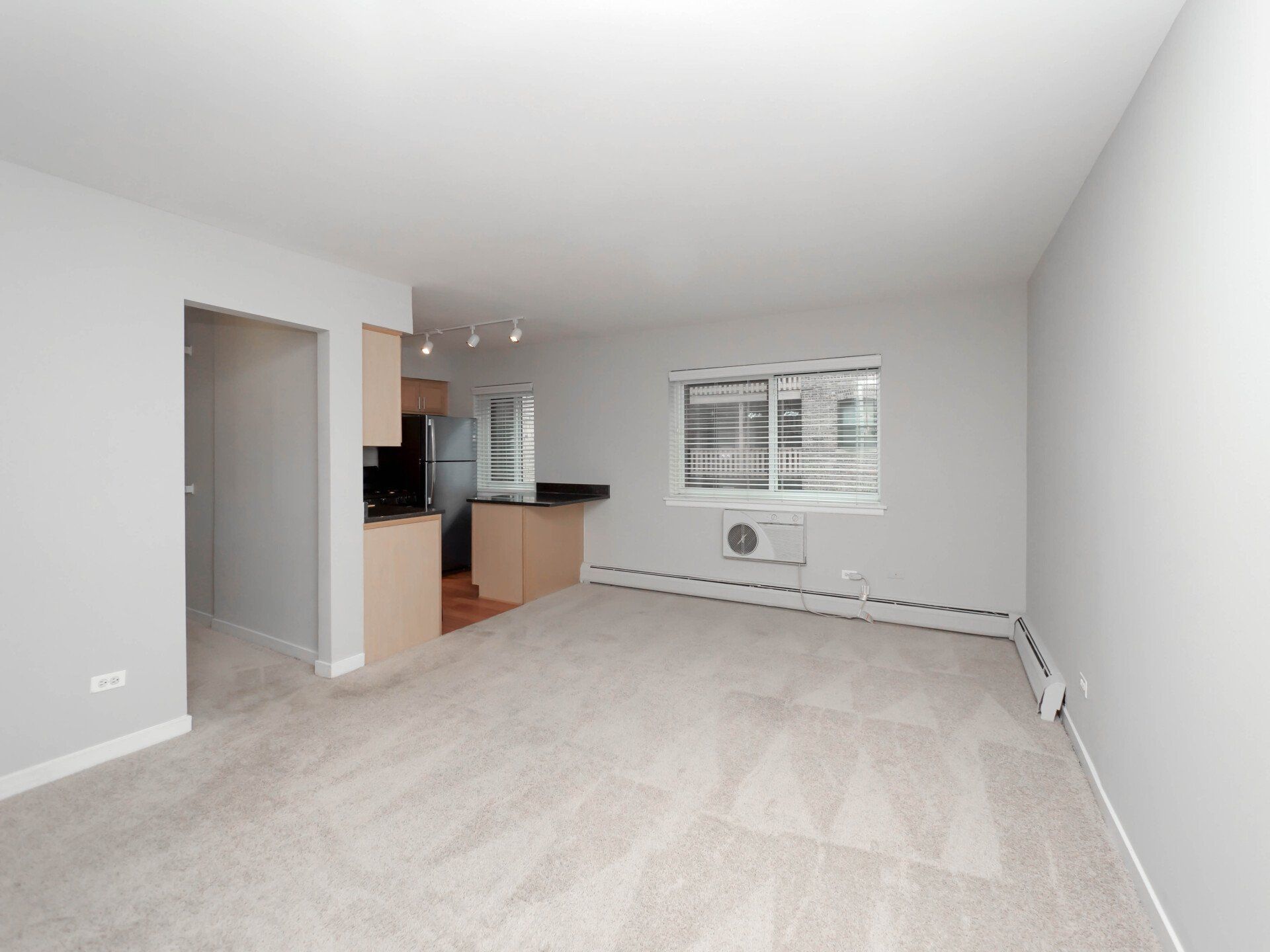 An empty living room with a kitchen in the background at Reside on Morse.