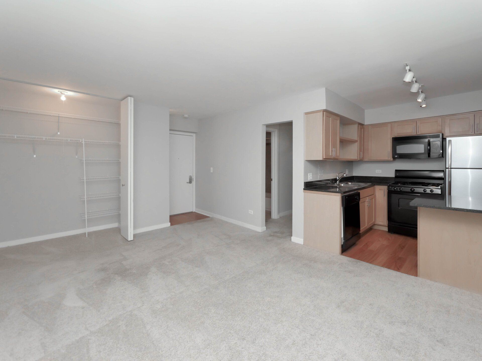 An empty apartment with a kitchen and a living room at Reside on Morse.
