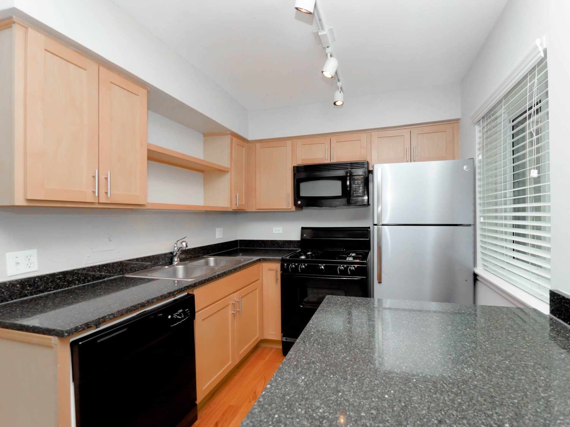 A kitchen with stainless steel appliances and granite countertops at Reside on Morse.