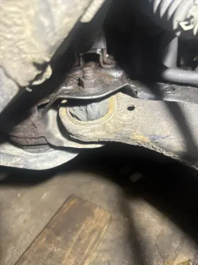 Rusting car suspension component, with a worn rubber bushing visible in the center.