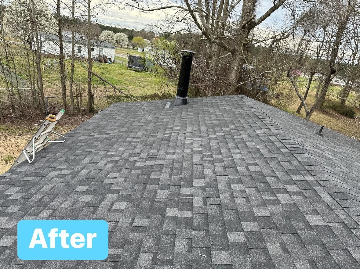 Newly shingled gray roof with a black chimney, trees, and a ladder on the side.