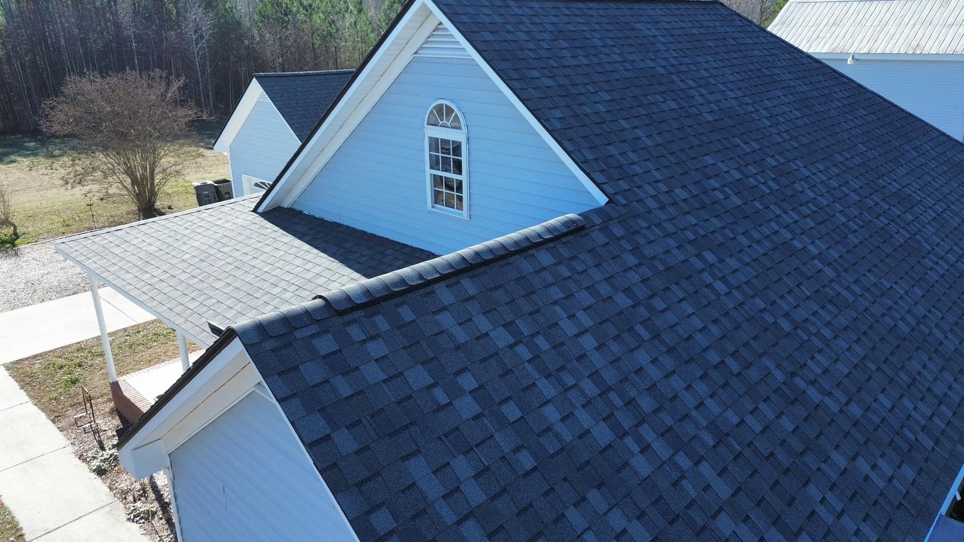An aerial view of a blue house with a black roof.