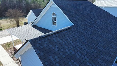 An aerial view of a blue house with a black roof.