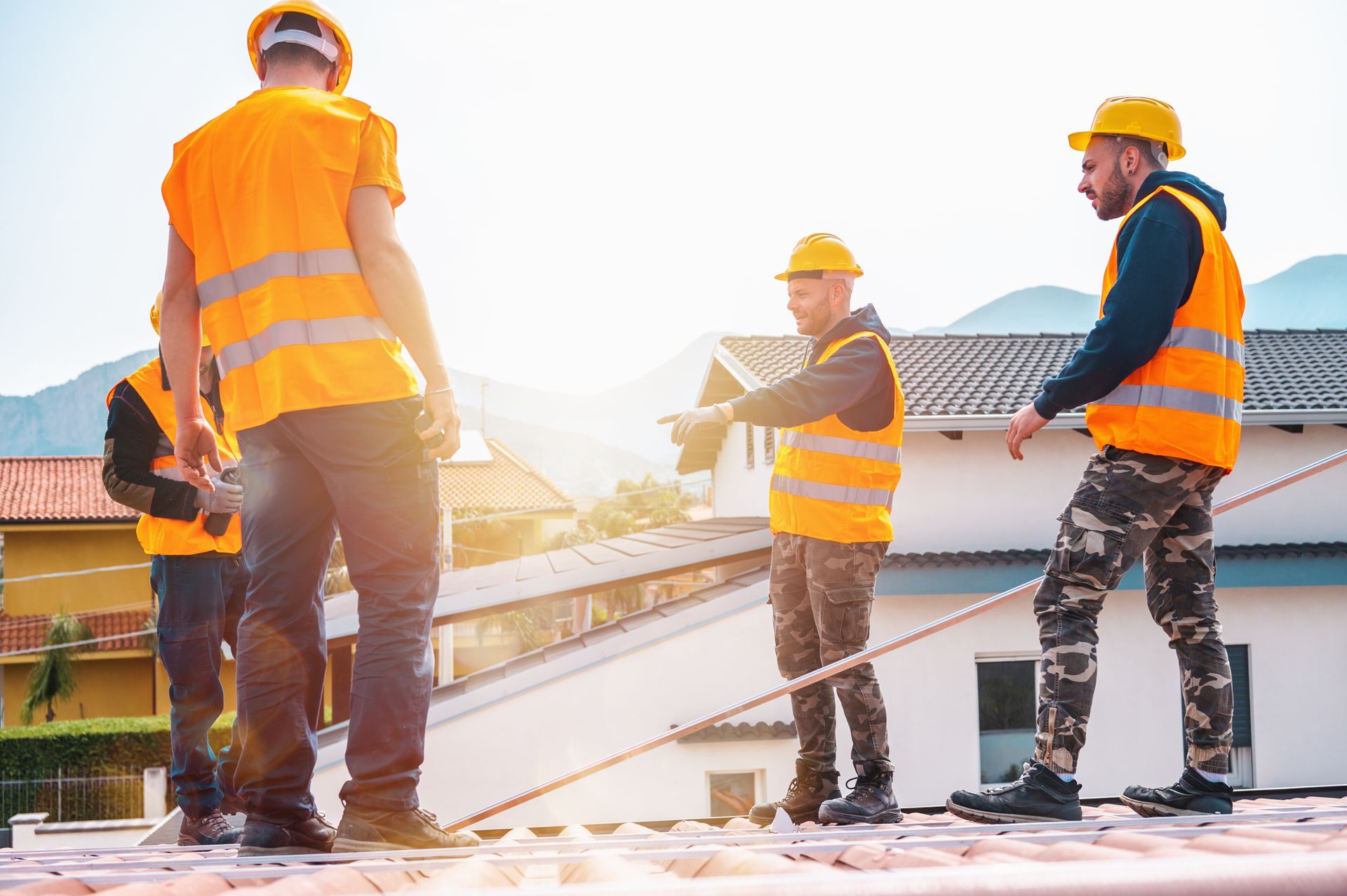 Three roofers installing new shingles on a residential roof.