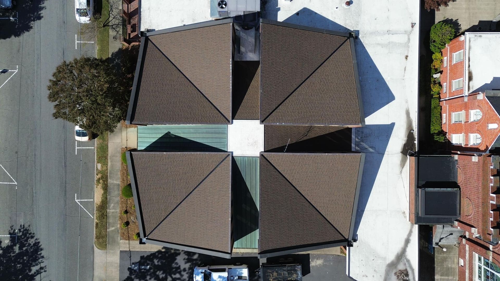 Overhead view of four buildings with brown, angular roofs meeting at a central white square.