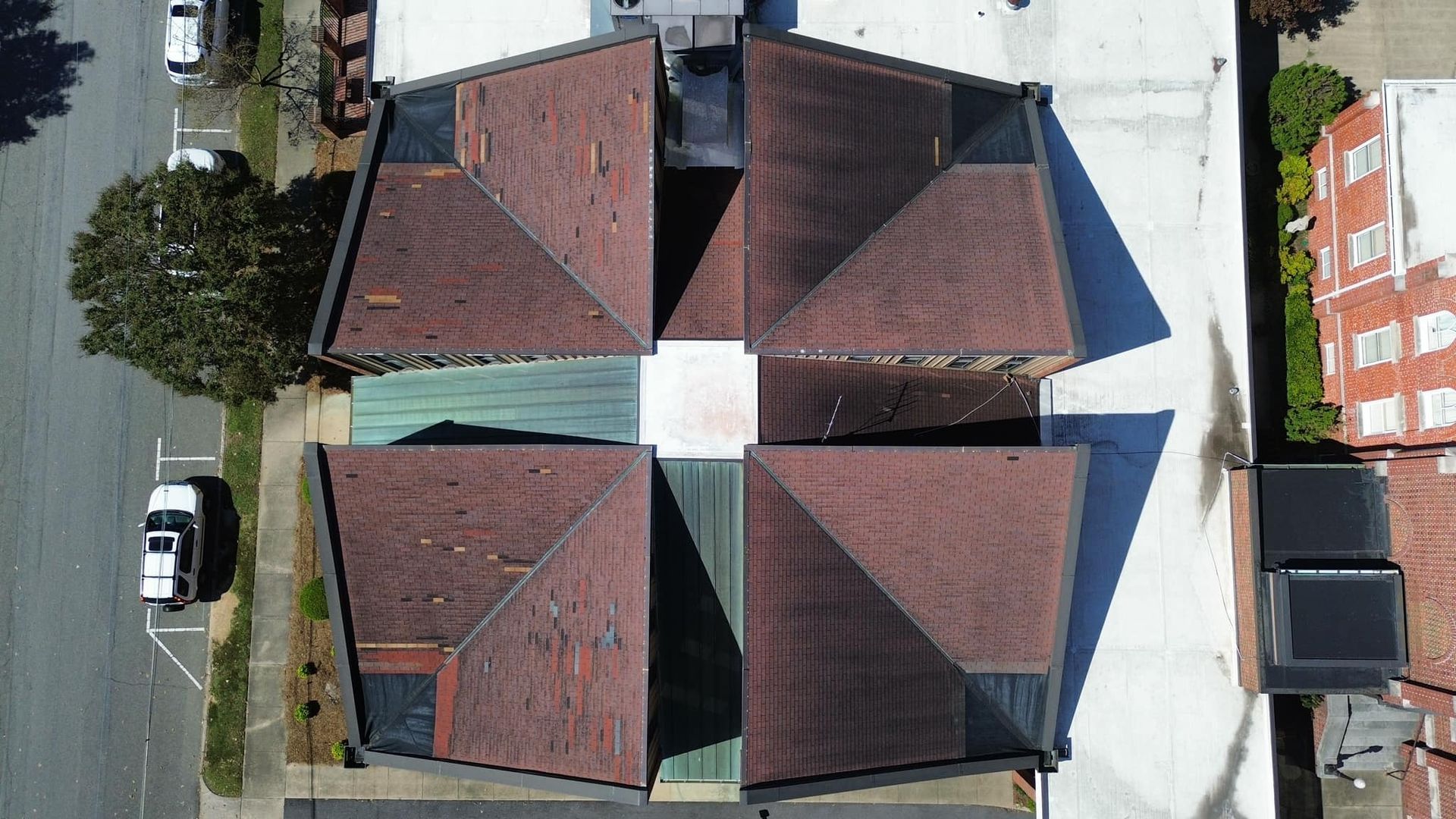 Aerial view of a four-section building with dark brown roofs.