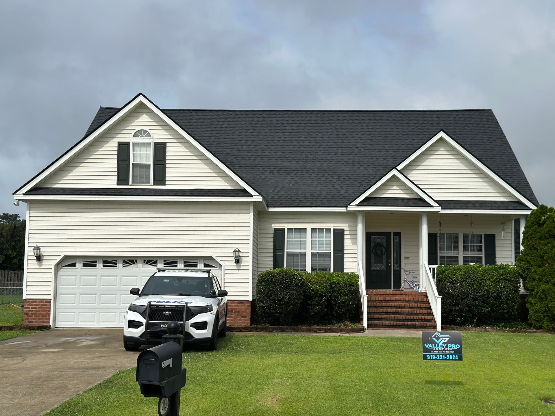 Brick chimney with black flashing on a brown shingle roof.