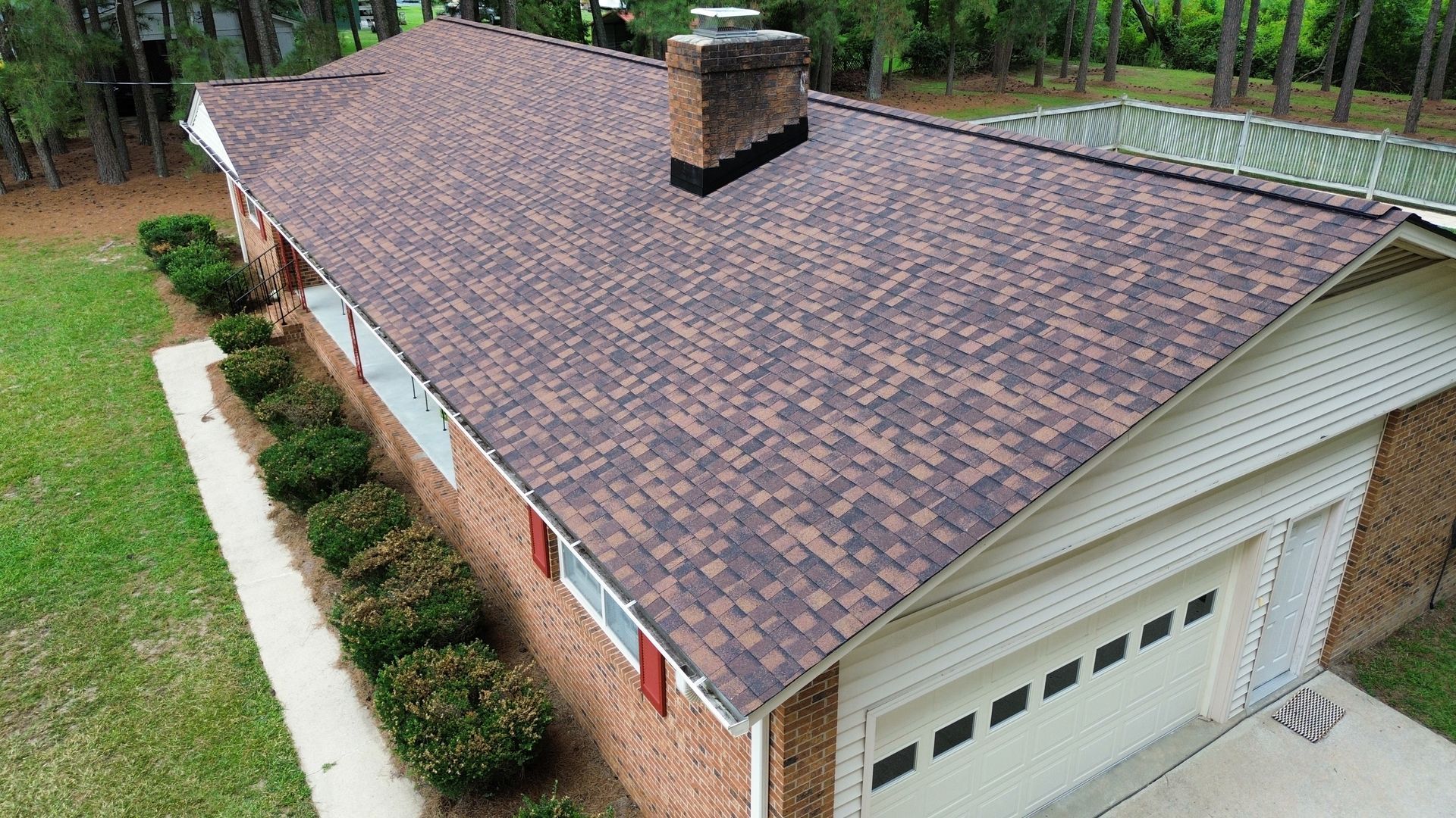 Brown shingled roof on a single-story brick and siding house with a chimney and garage.