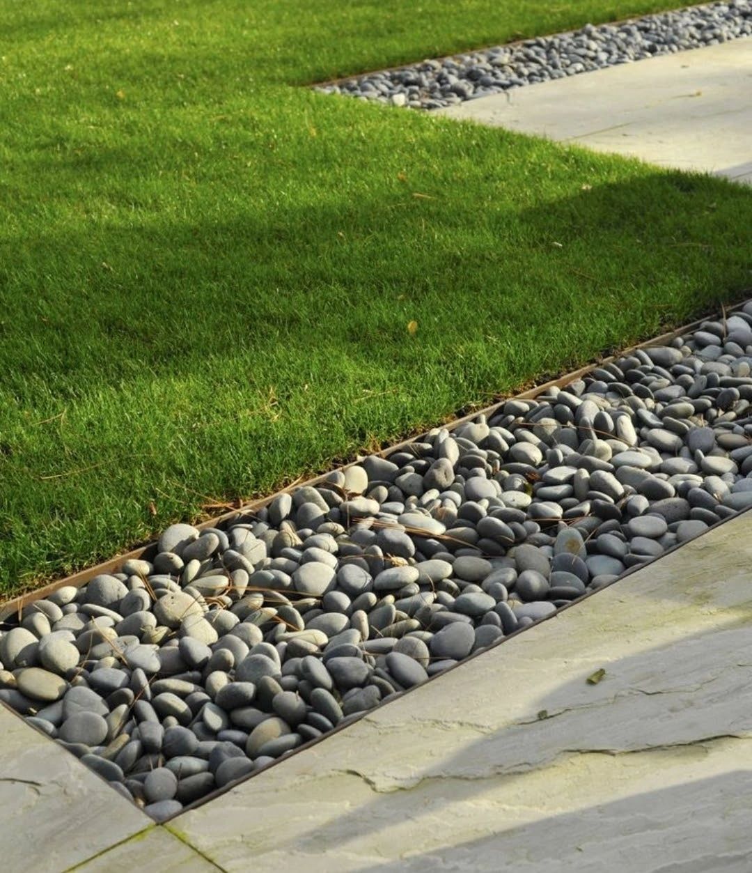 A stone walkway leading to a lush green lawn