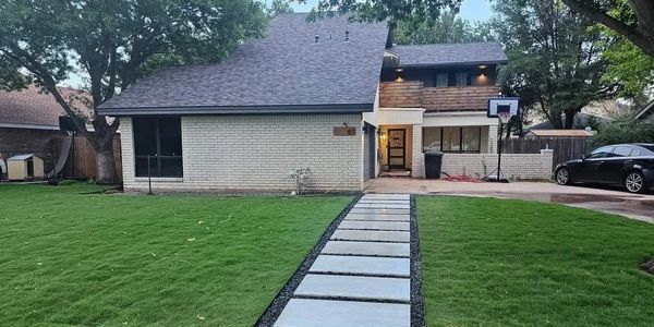 A house with a basketball hoop in front of it and a car parked in front of it.