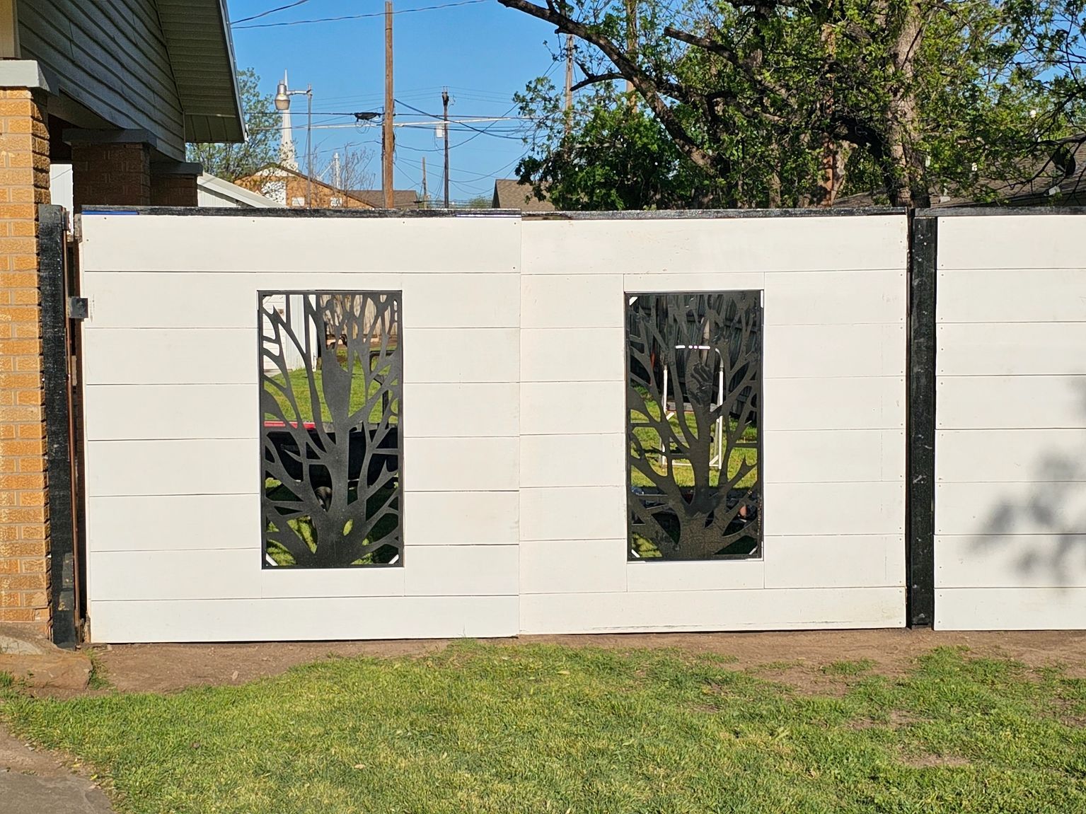A white fence with a tree design on it is in front of a house.
