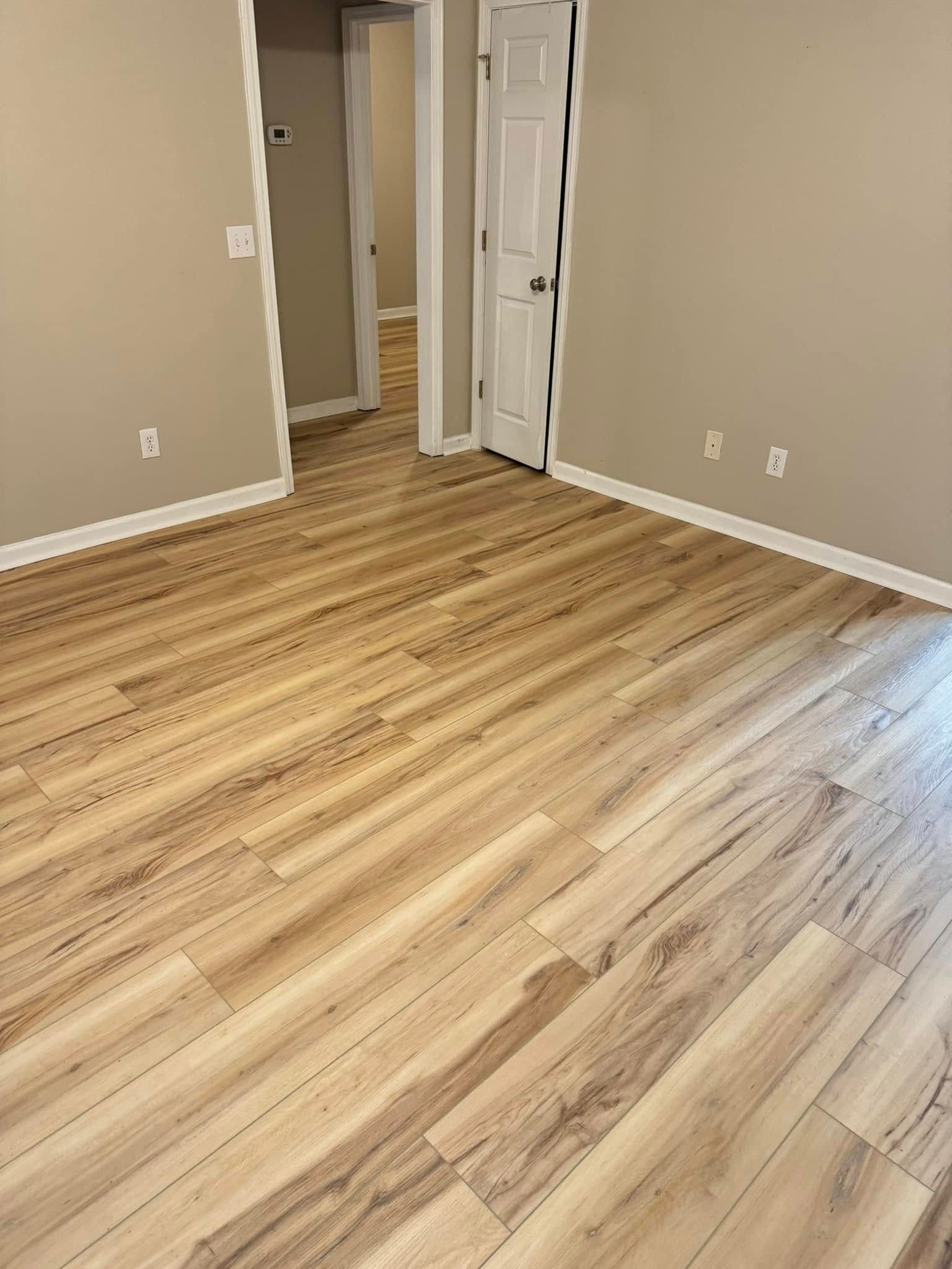 An empty room with hardwood floors and beige walls.