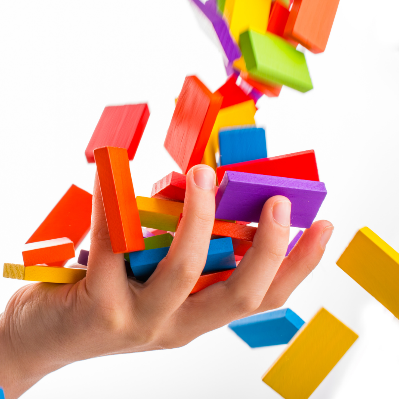 Hand releasing a cascade of colorful dominoes.
