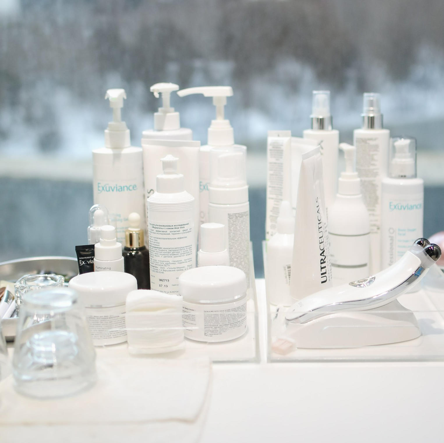 A table full of white cosmetic bottles and jars including one that says excellence