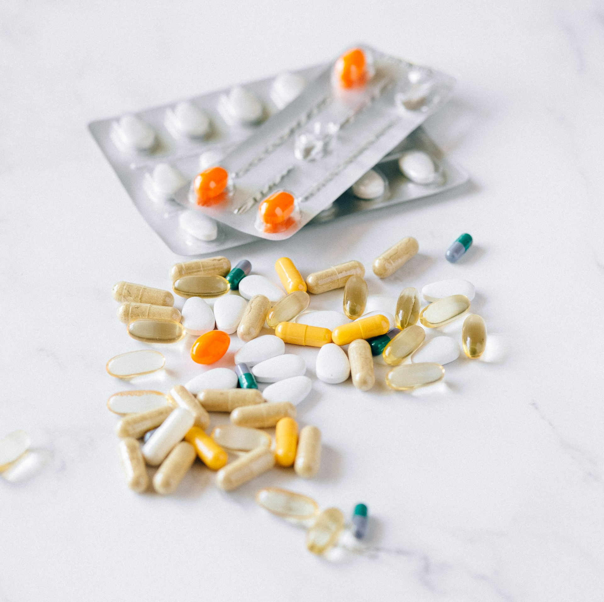 A pile of pills and a blister pack of pills on a table.