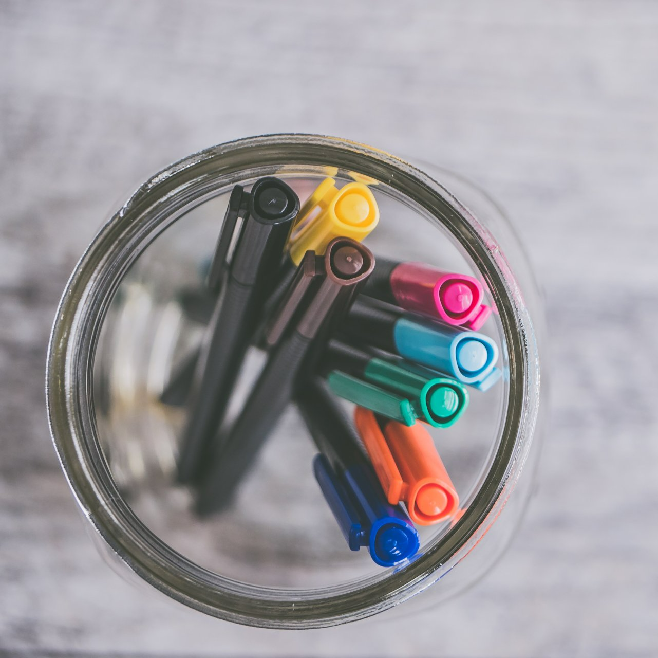 A glass jar filled with markers of different colors