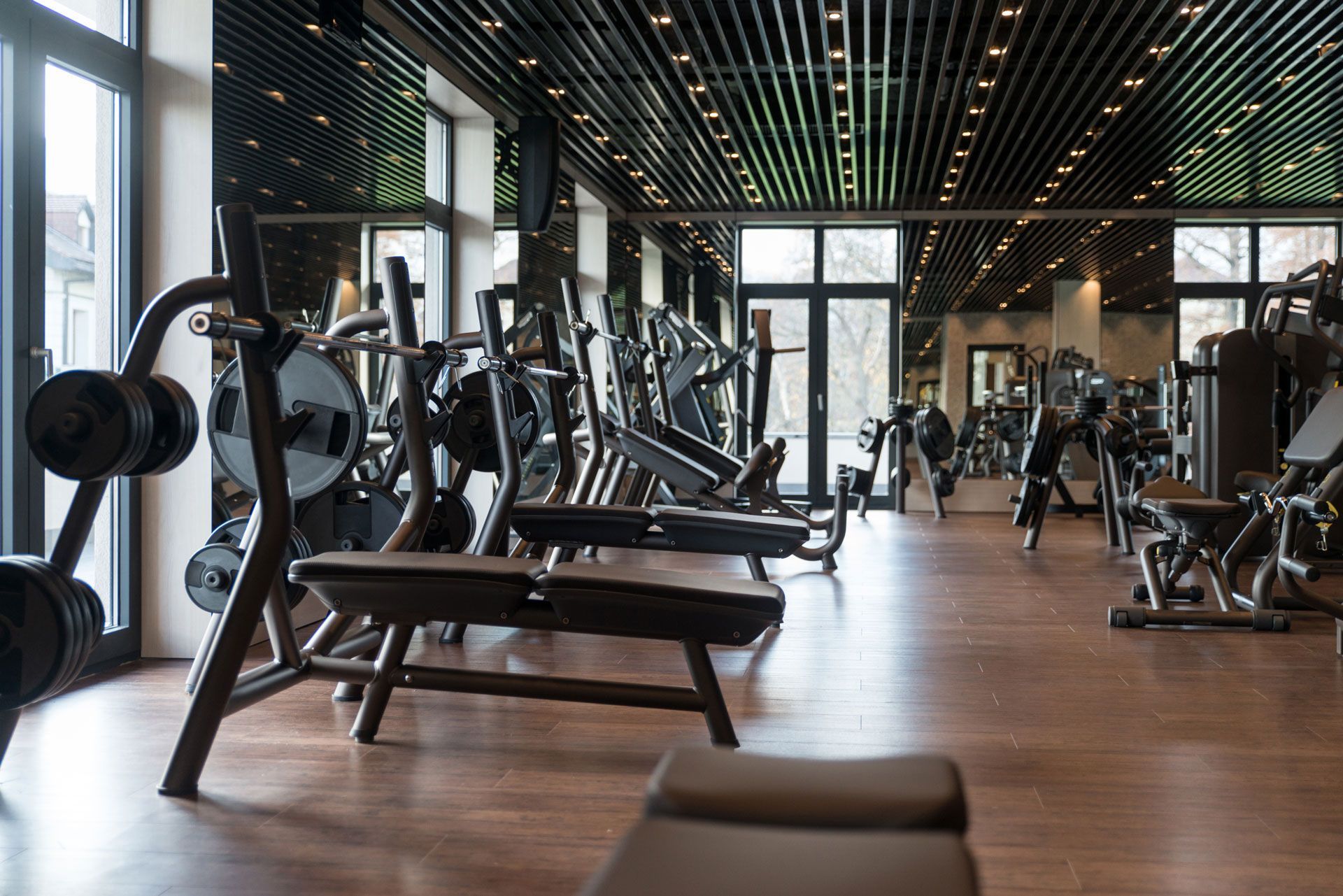 Gym interior with weight machines, benches, and a wooden floor.