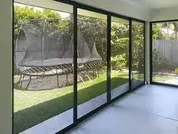 Glass Doors Looking Onto a Backyard With Trampoline, Grass, and Trees — Big Tom's Security Screens in Farleigh, QLD