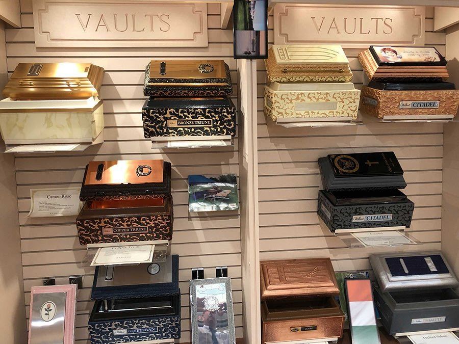 Display of various vaults in a store, including gold, bronze, and patterned designs. 