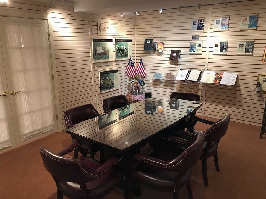 Conference room with a large table, chairs, displays on the wall, and American flags.