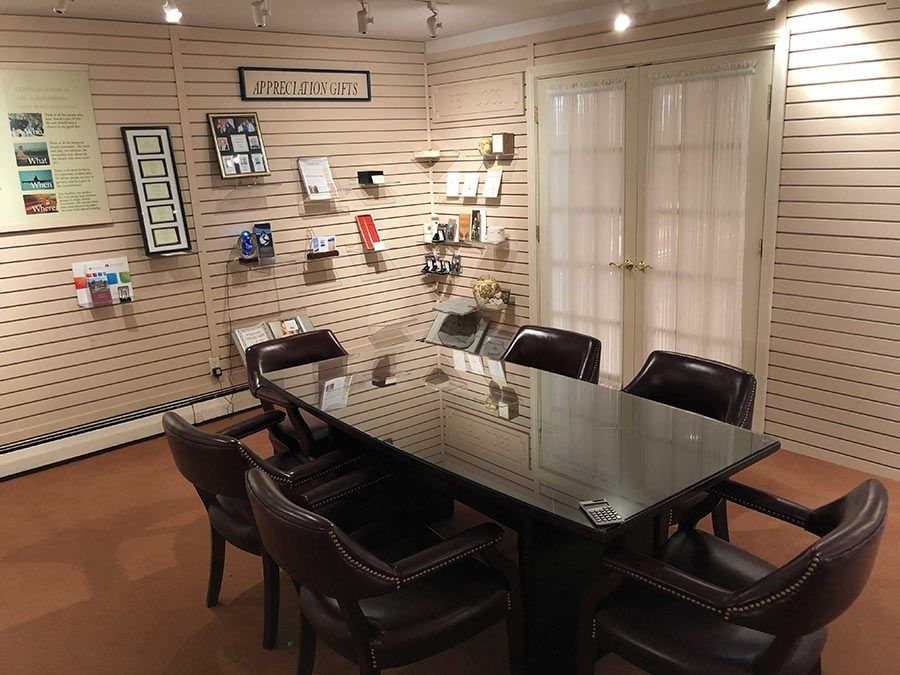 A conference room with a black table and leather chairs, display shelves on the walls and double doors.