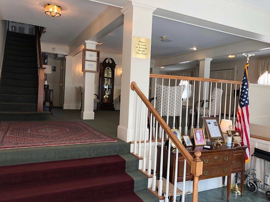 Interior of a building with staircase, grandfather clock, and American flag.