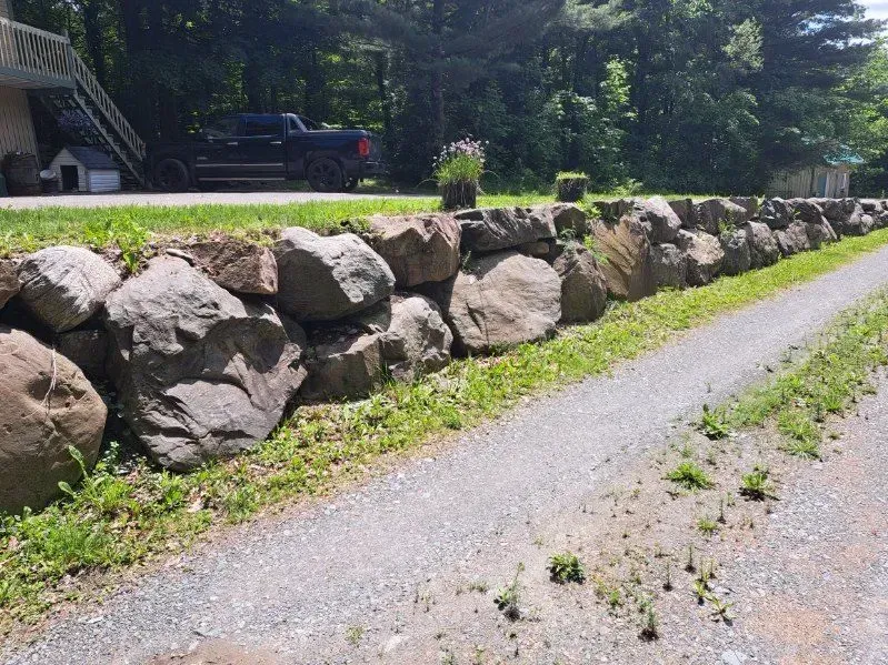 Un grand mur de pierre le long d'une route.