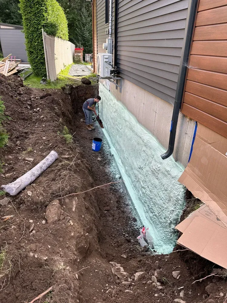 Un homme dépose de la mousse sur le côté d'une maison.
