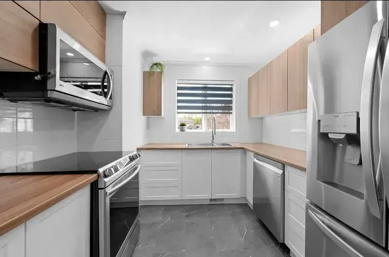 Une cuisine avec des appareils électroménagers en acier inoxydable et des armoires en bois.