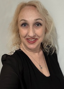 A woman with blonde hair is wearing a black shirt and a necklace.