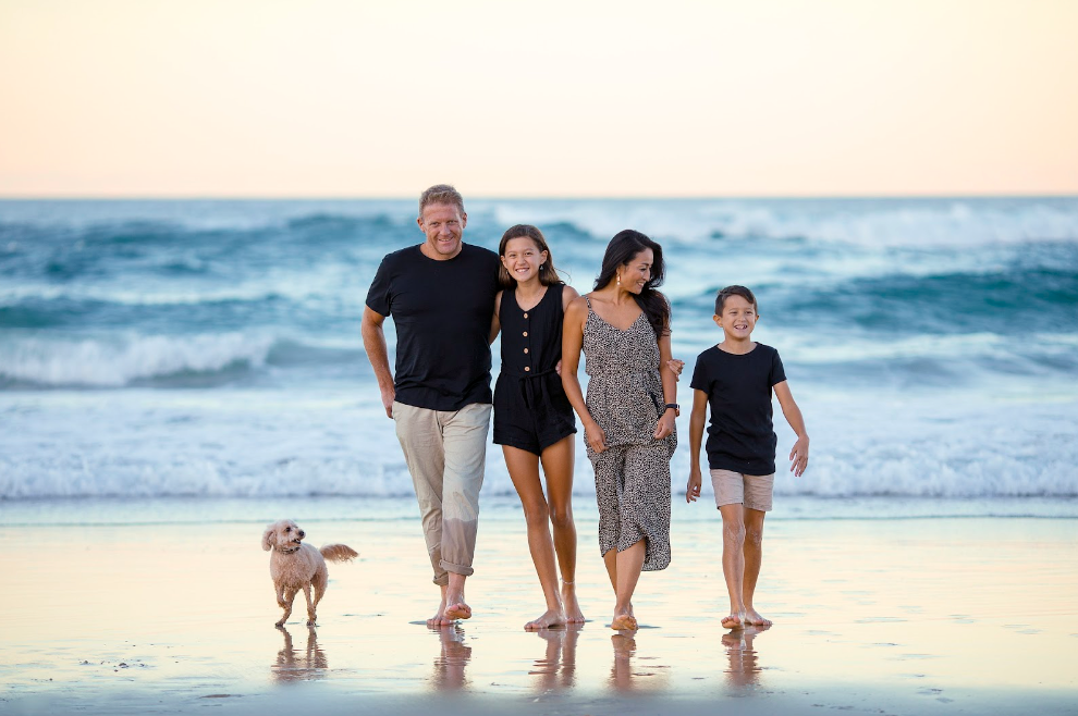 A family is walking their dog on the beach.