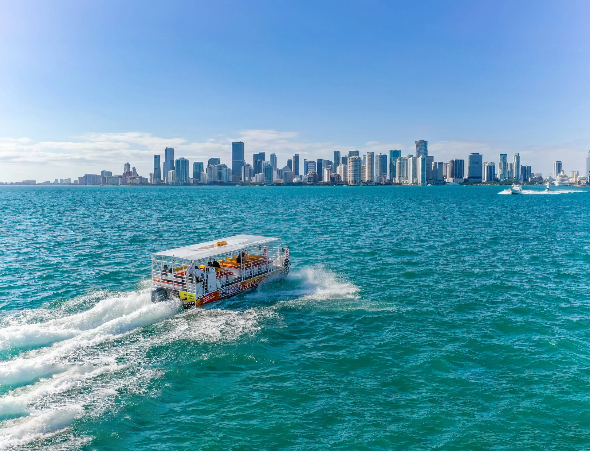 A boat is floating on top of a body of water with a city skyline in the background.