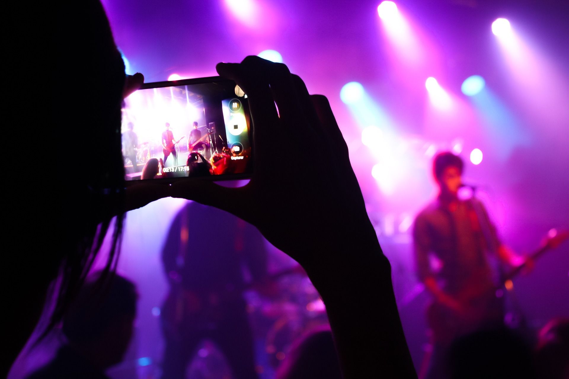 A person is taking a picture of a band on stage