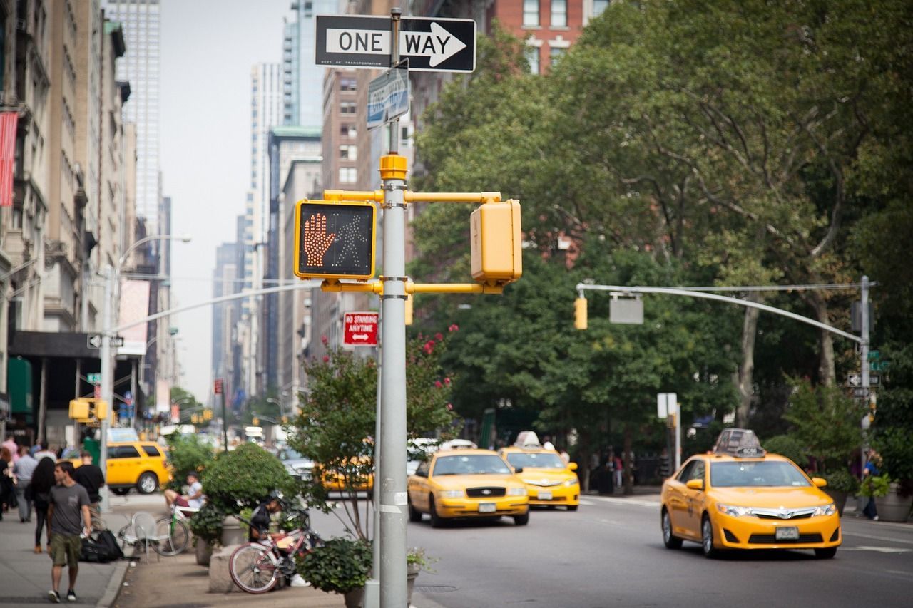 A row of yellow taxis are driving down a city street.