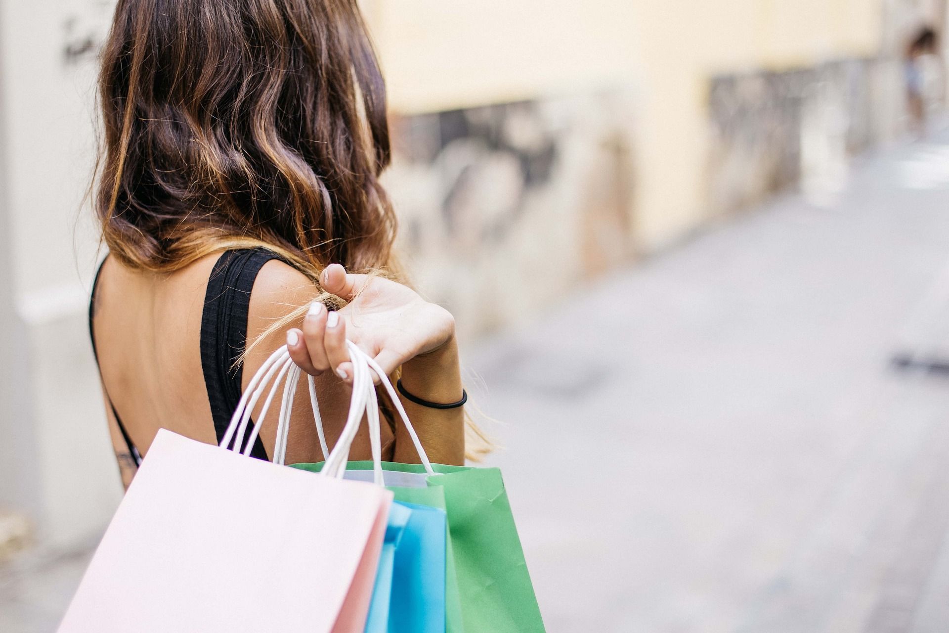 A woman is holding a bunch of shopping bags over her shoulder.