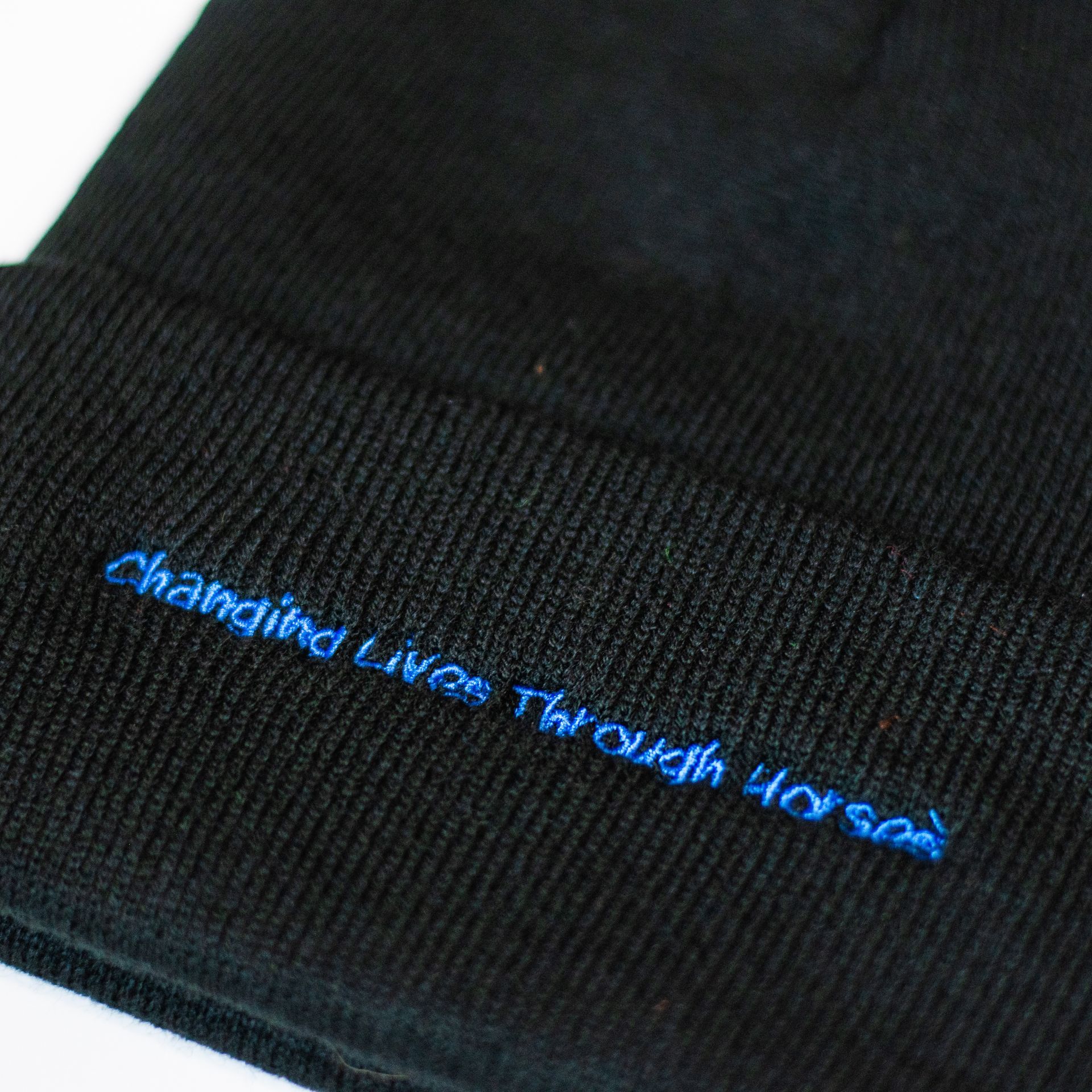 A black beanie with the words changing lives through hospice embroidered on it