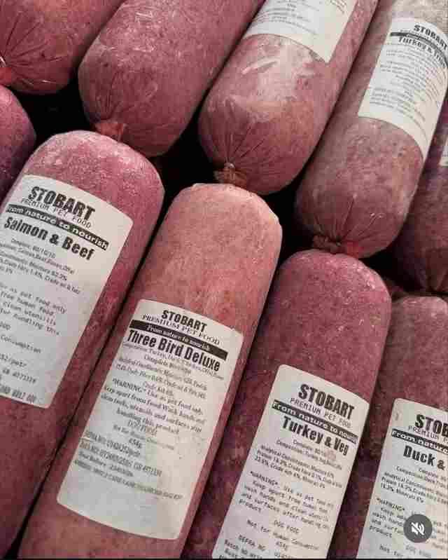 Several tubes of frozen raw pet food, labeled by flavor like Salmon & Beef and Three Bird Deluxe, arranged in a pile.